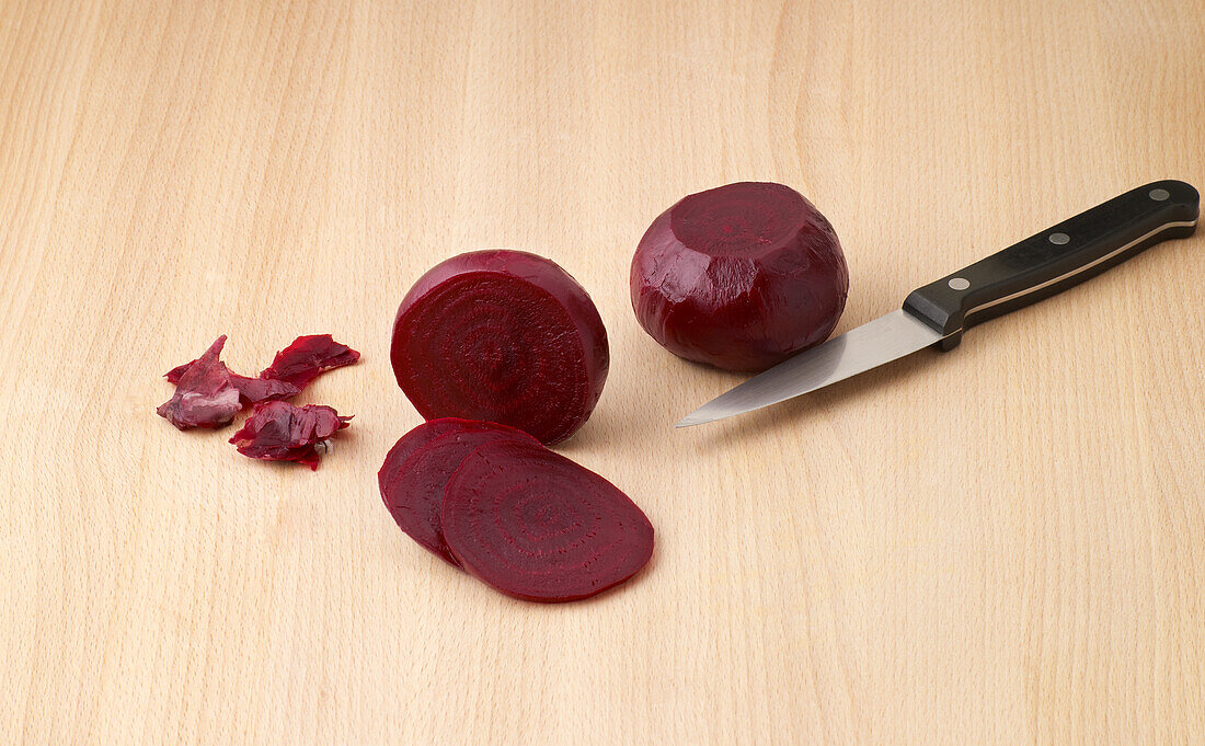 Cooked beetroot with slices beside knife
