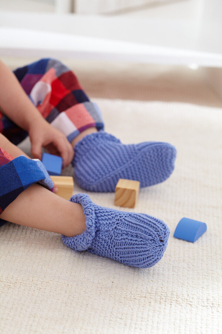 Boy playing with blocks wearing knitted slippers
