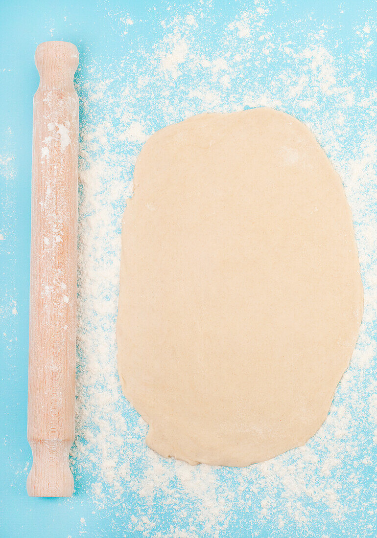 Wooden rolling pin and rolled flat pastry