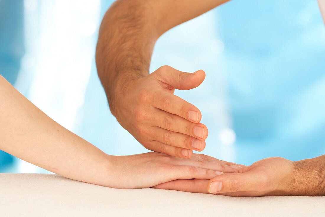 Reflexologist massaging woman's hand using tapping technique
