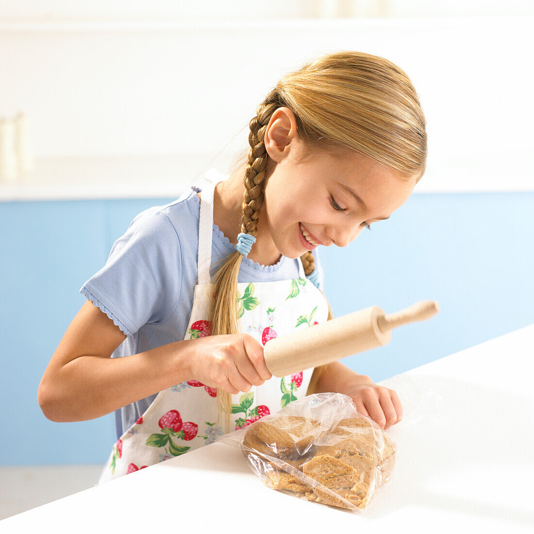 Girl crushing biscuits in a bag with a rolling pin