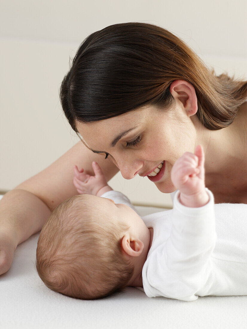 Woman lying looking over a baby boy lying on his back