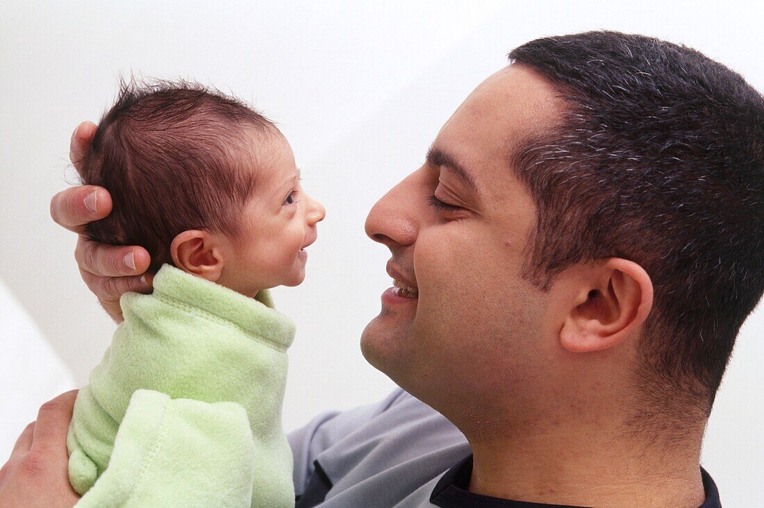 Man holding a small baby close to his face