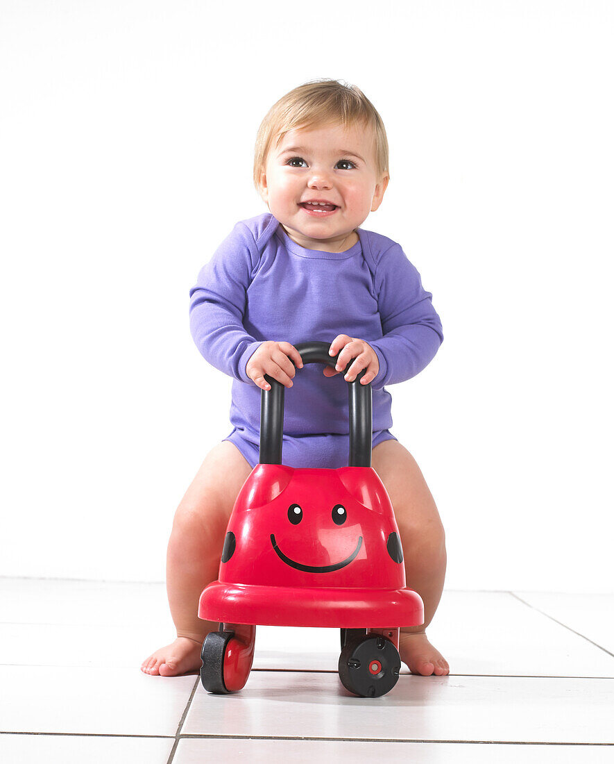 Baby girl sitting on a ride on ladybird toy
