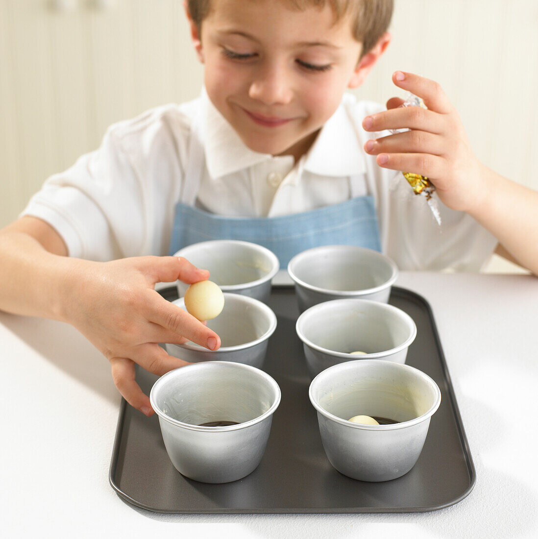 Boy adding white chocolate truffles to moulds