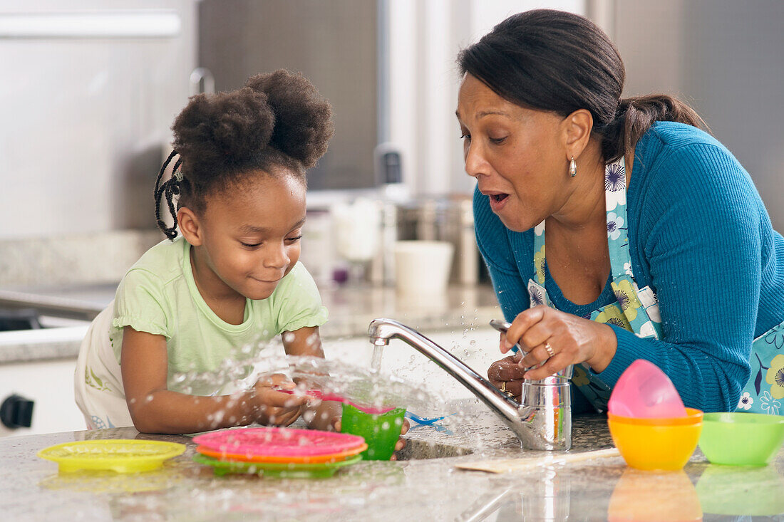 Woman and young girl doing washing up