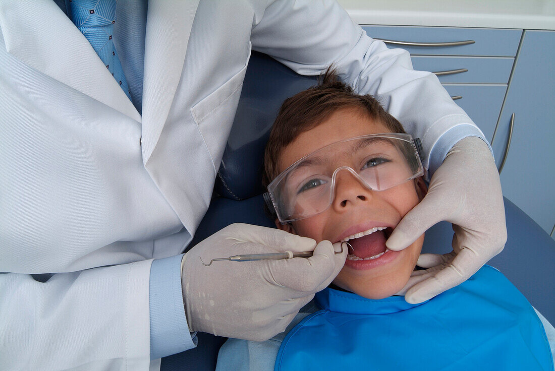 Dentist holding periodontal probe in boy's mouth
