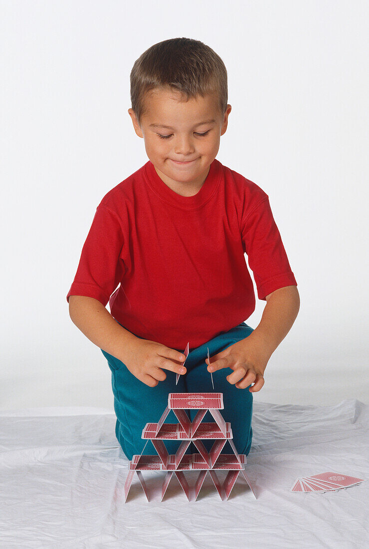 Smiling boy building a house of cards