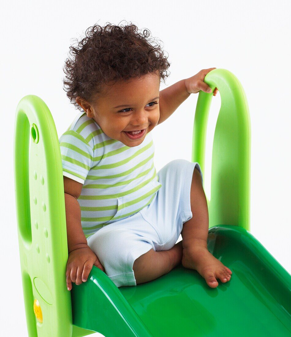 Toddler boy sitting at top of plastic slide