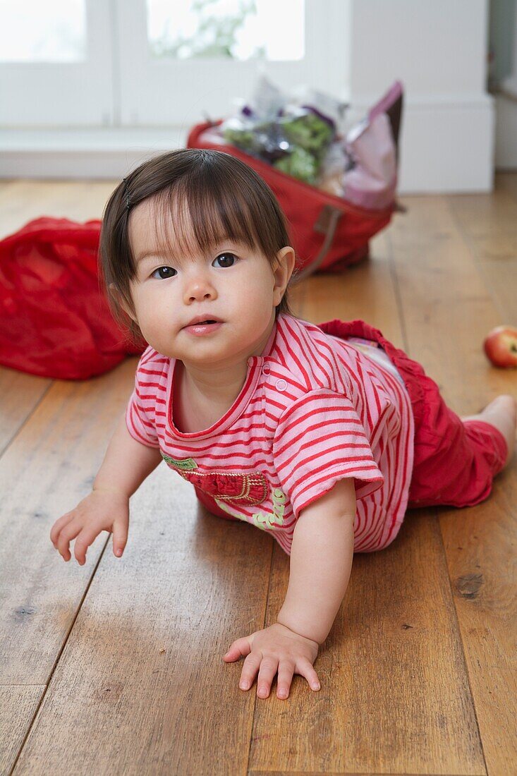 Baby girl crawling on wooden floor