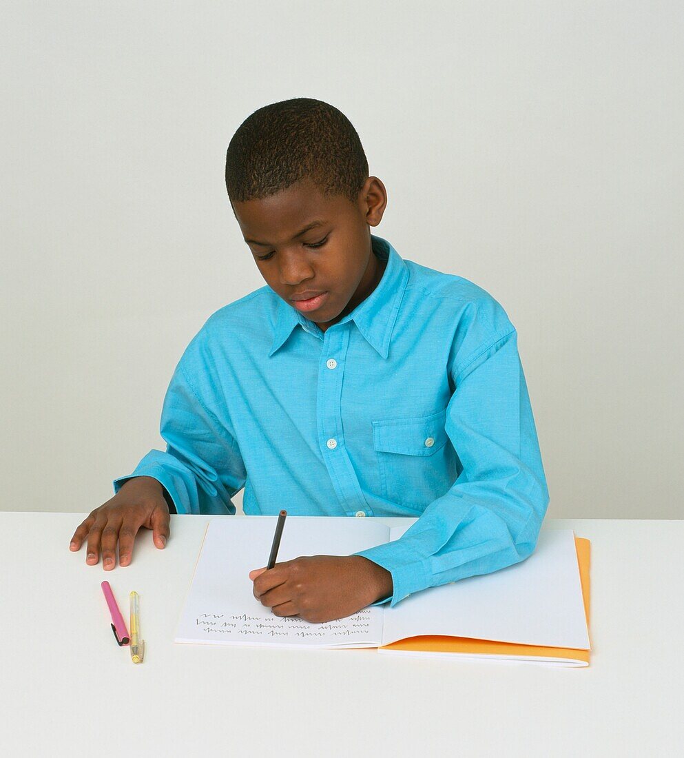 Boy writing in exercise book on desk