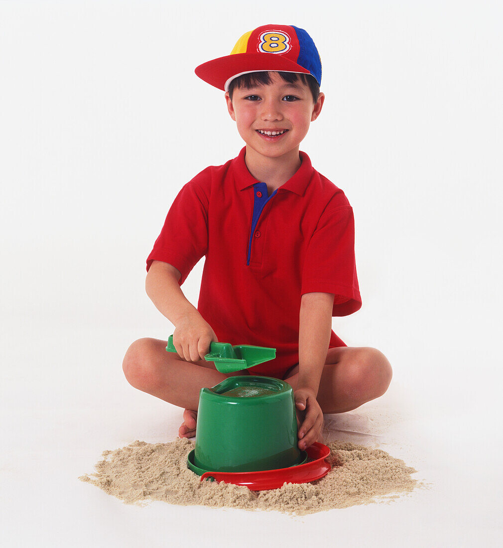Boy sitting cross legged making a sandcastle