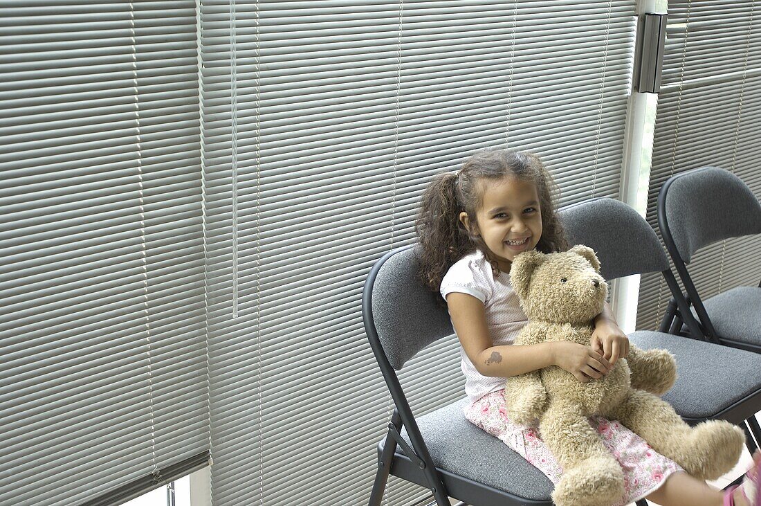 Girl holding teddy bear in waiting room
