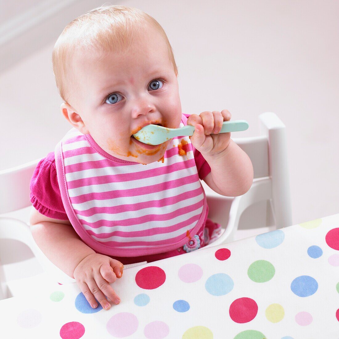 Baby girl holding spoon to mouth