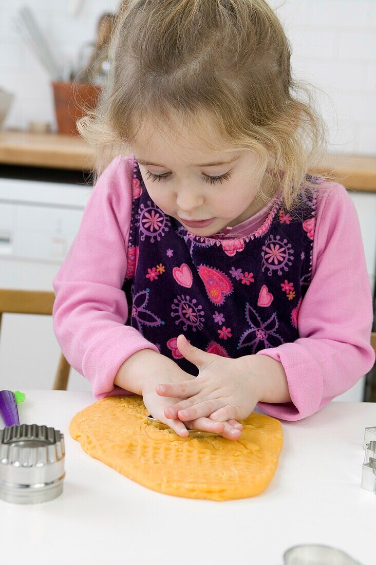 Girl pressing biscuit cutter into dough