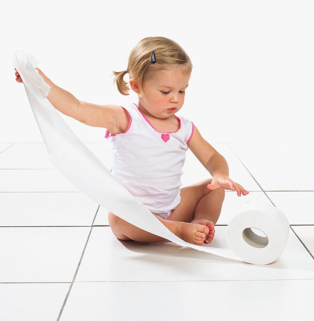 Toddler girl in underwear pulling at toilet roll