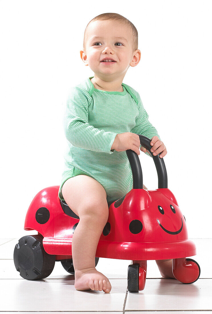 Baby boy sitting on ride on ladybird toy
