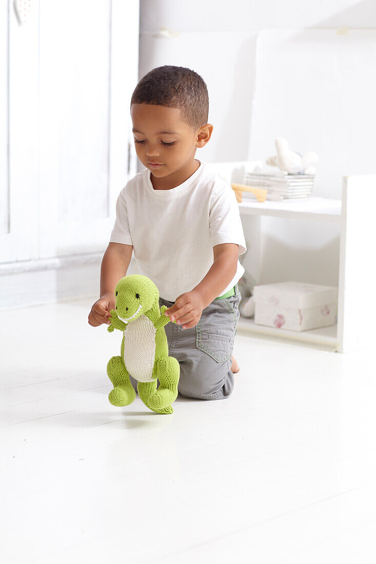 Boy playing with knitted dinosaur toy