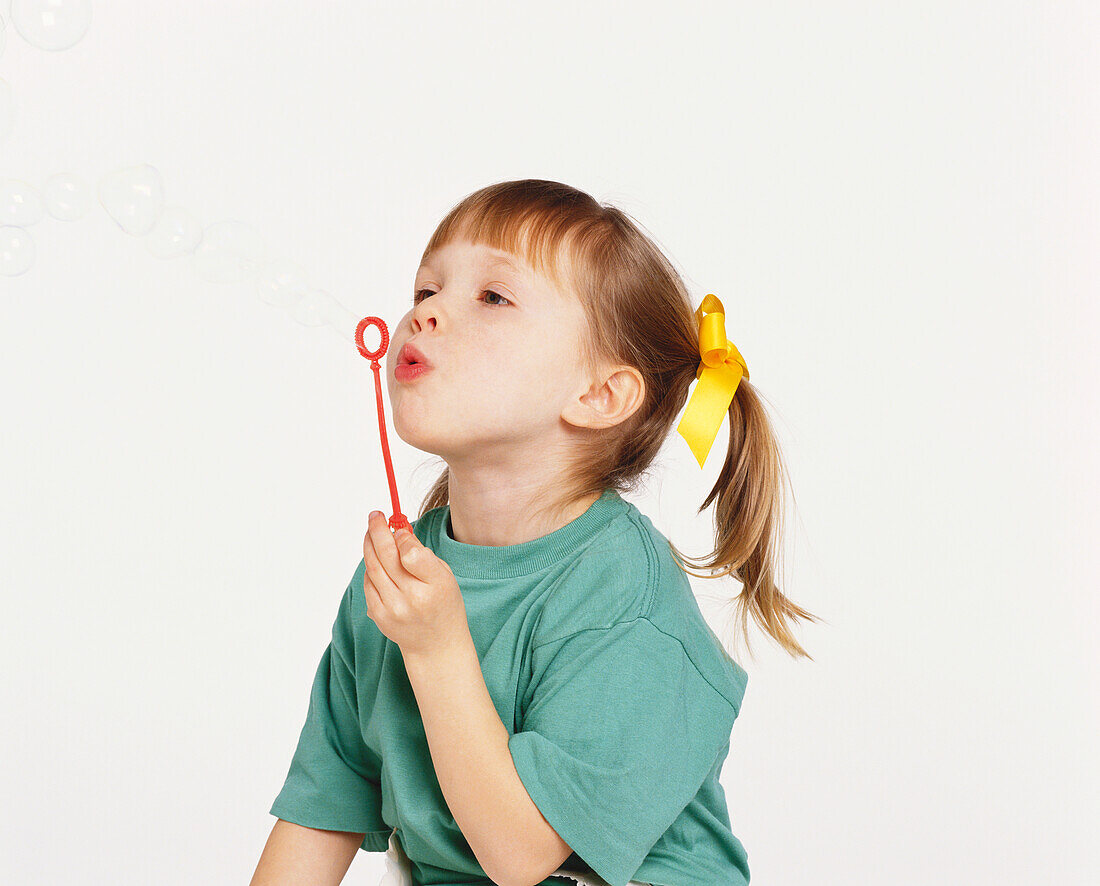 Girl blowing bubbles through plastic wand
