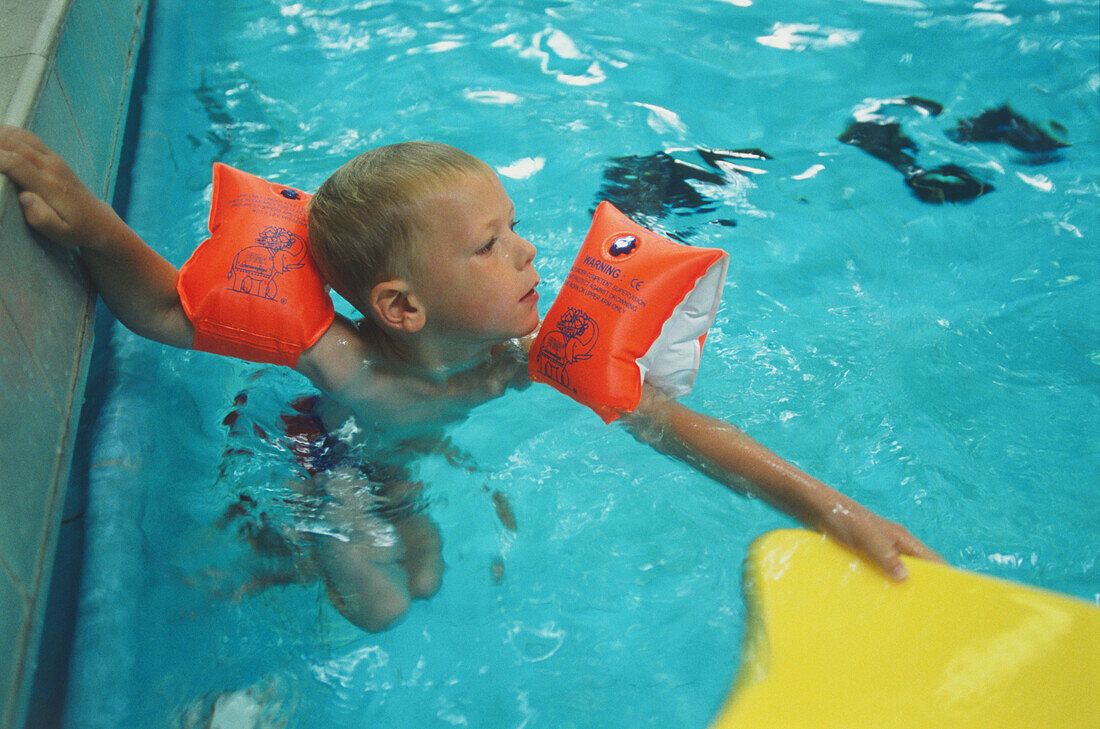 Boy in pool wearing arm bands