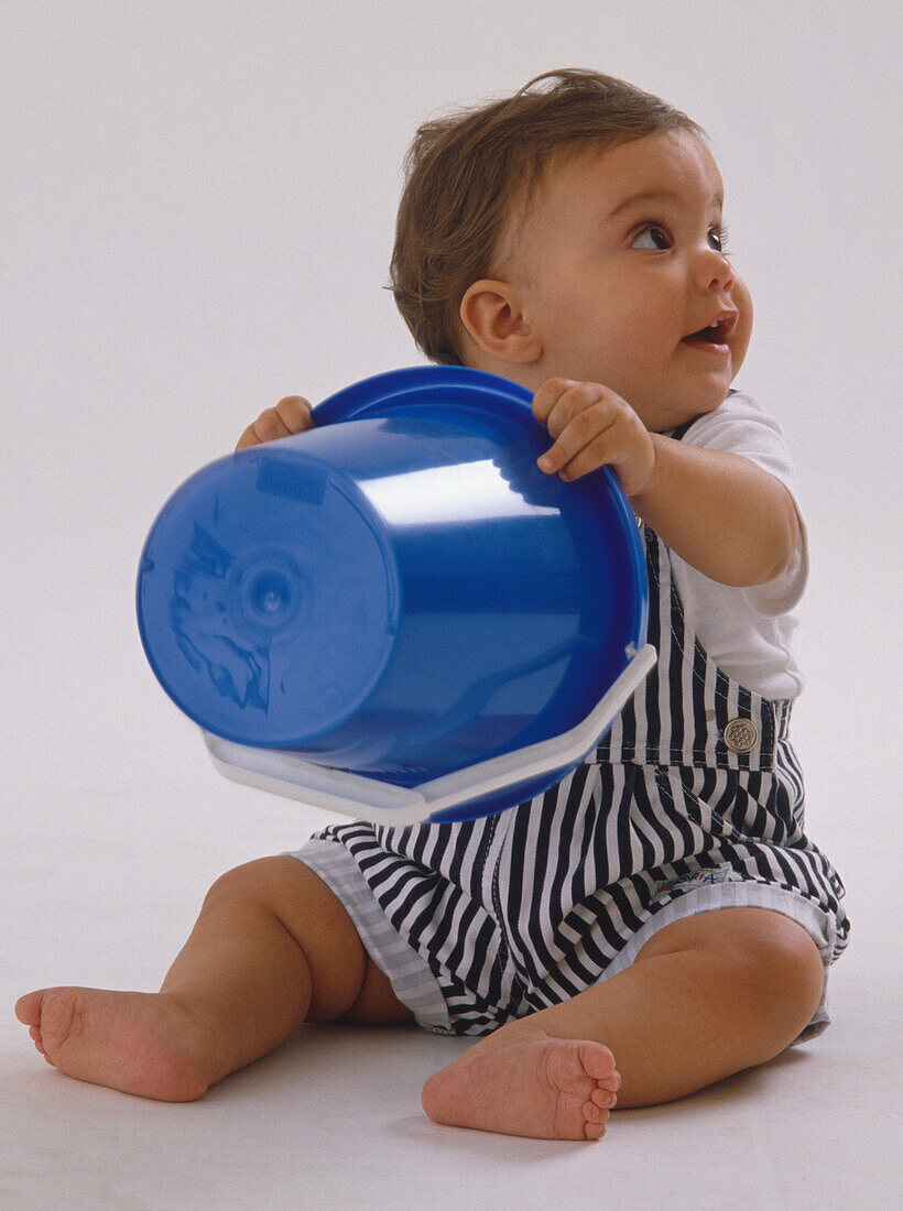 Baby clutching plastic bucket