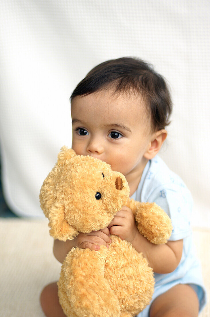 Baby boy kissing teddy bear