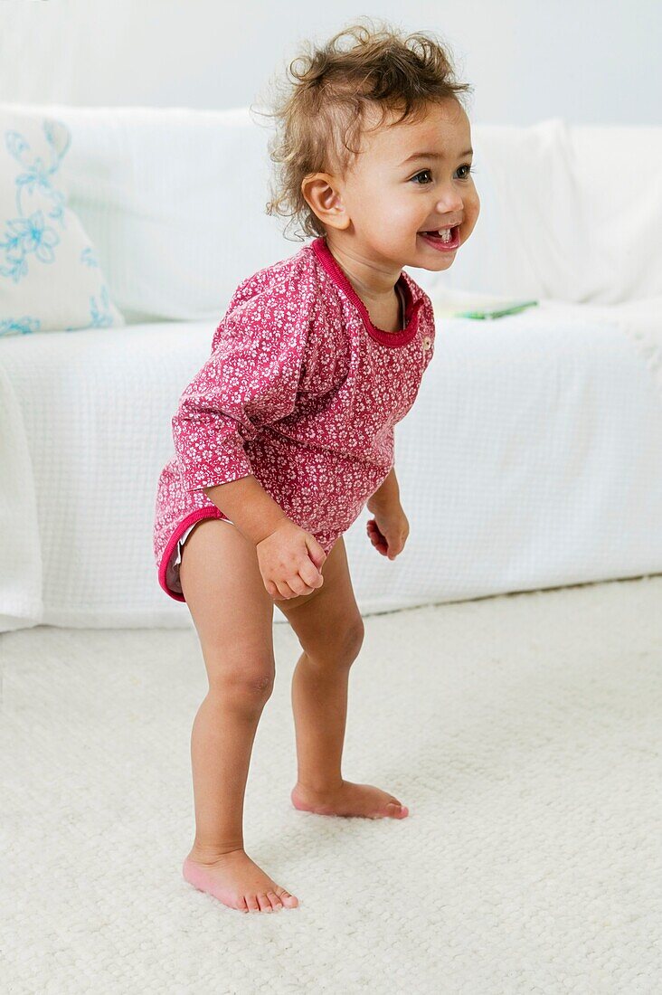 Baby girl standing up and smiling