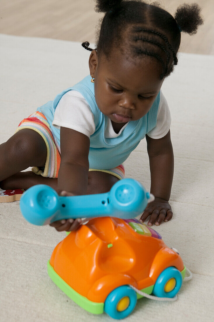 Baby girl playing with plastic toy telephone