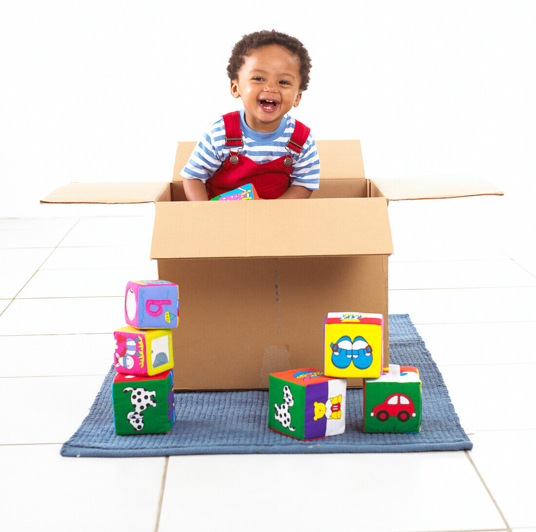 Boy standing inside a cardboard box holding a cube