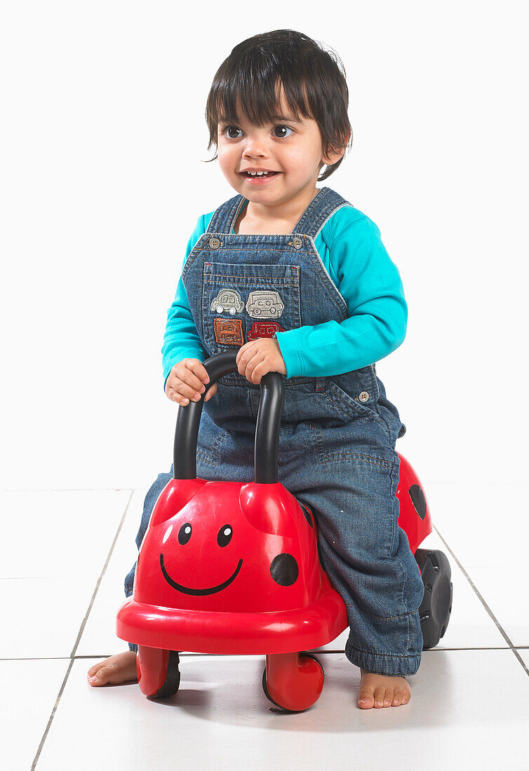 Young boy sitting on ladybird push along toy