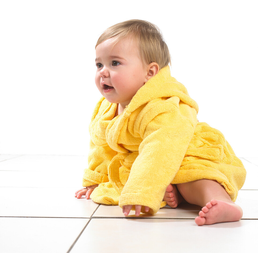 Baby girl sitting wearing yellow dressing gown