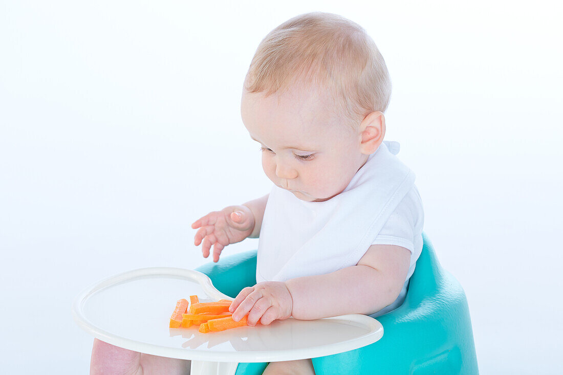 Baby boy eating carrot sticks
