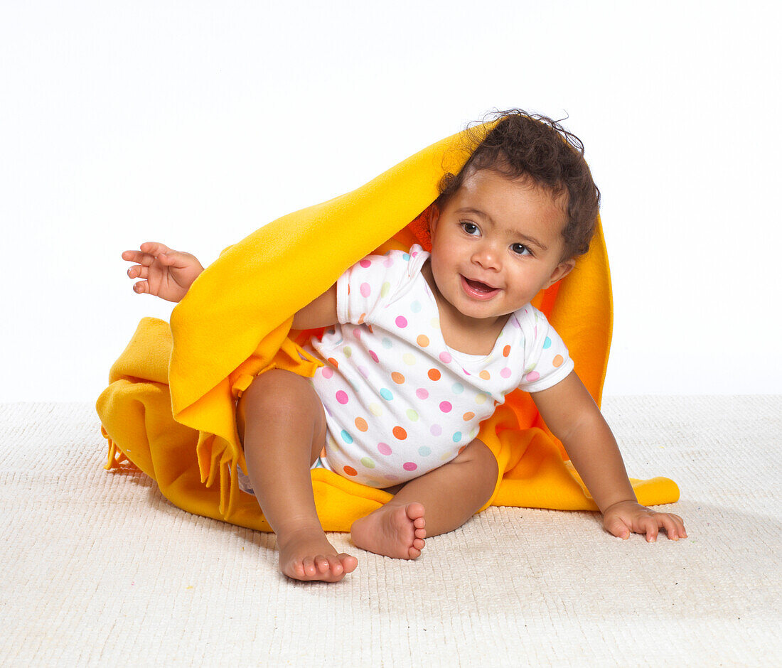 Baby girl partially covered with yellow blanket