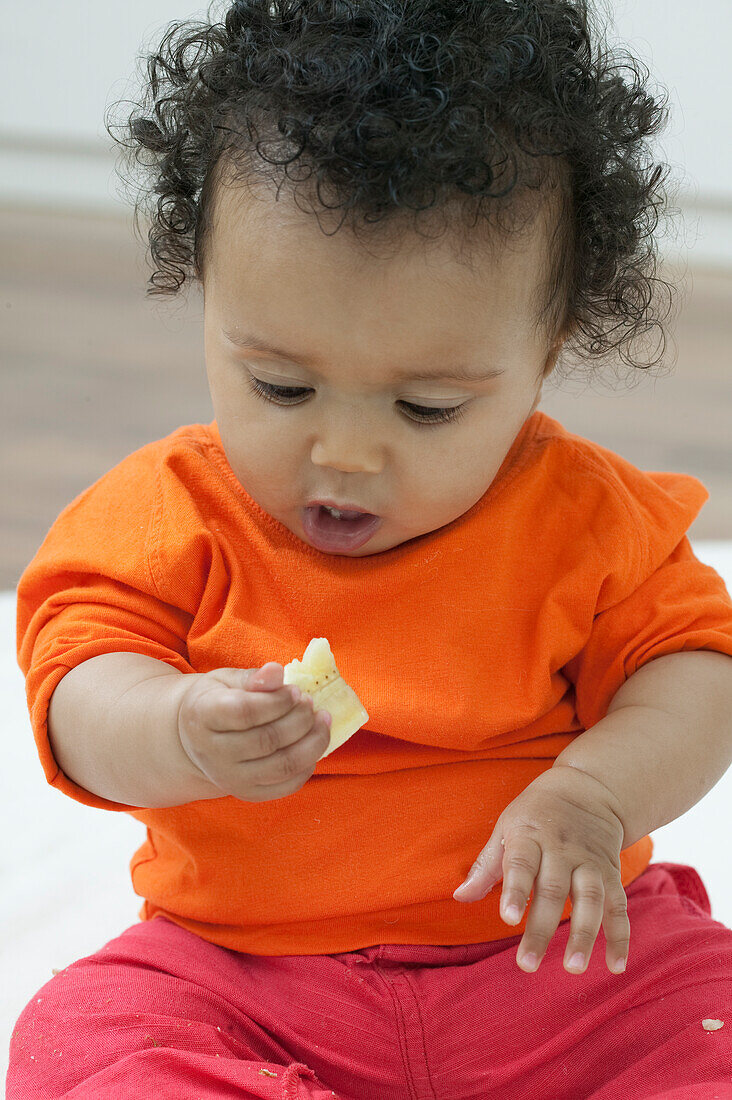 Baby girl looking at rice cracker