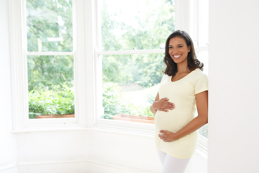 Smiling woman pregnant with twins with hands on bump
