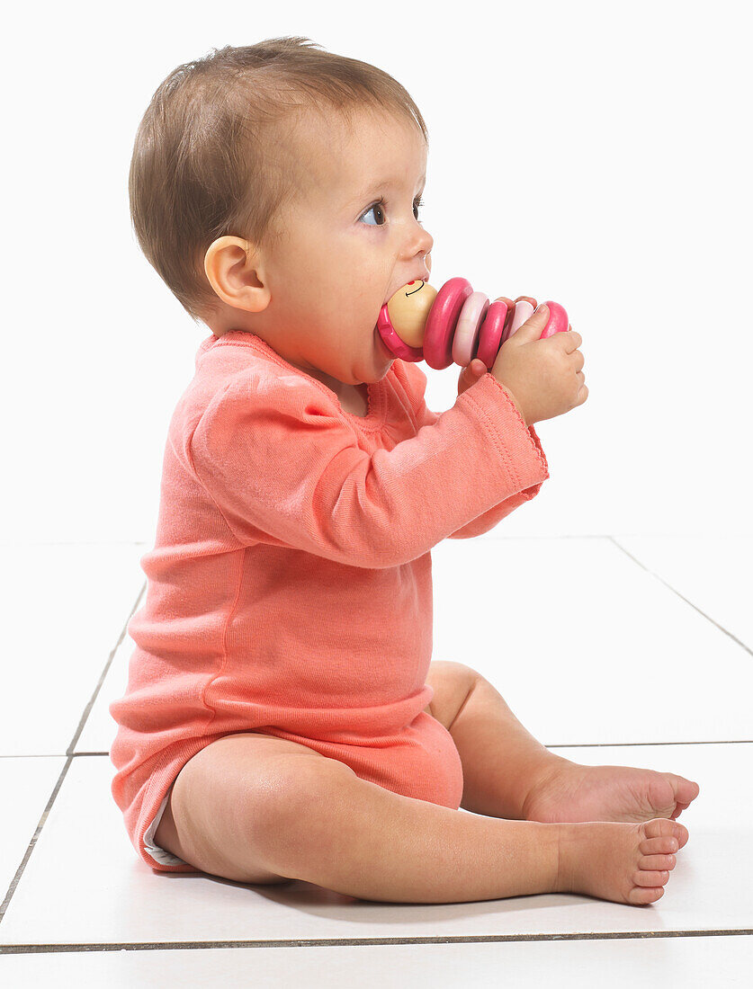 Baby girl with toy in mouth