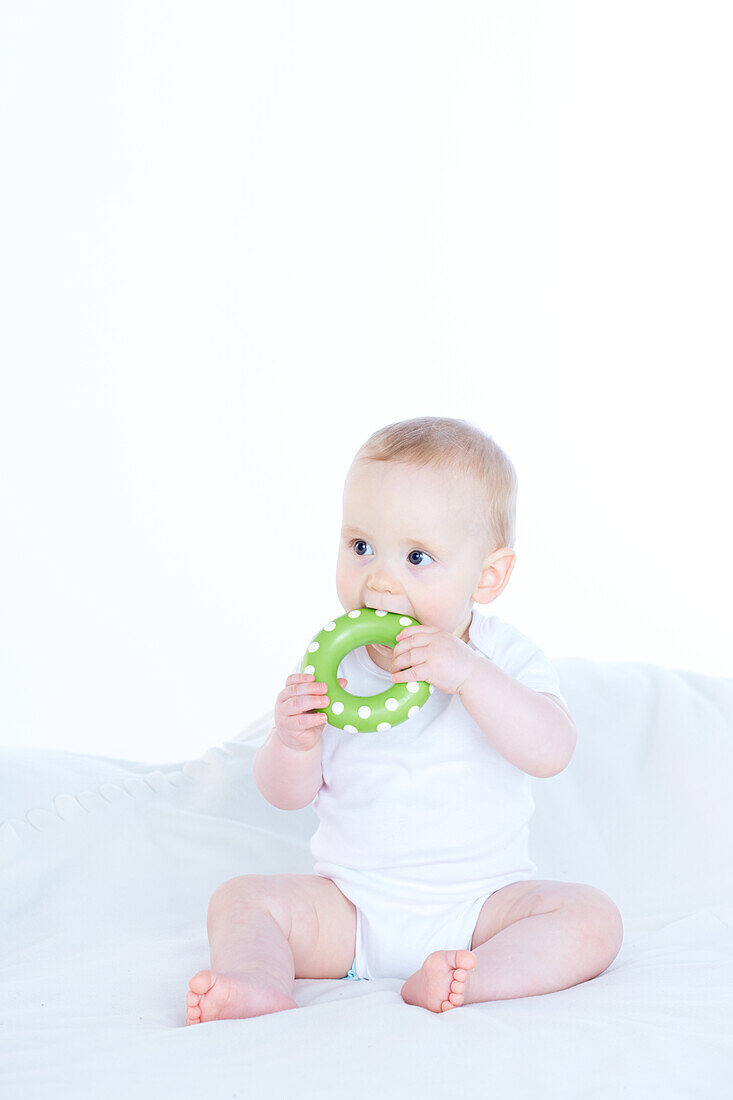 Baby boy chewing plastic ring