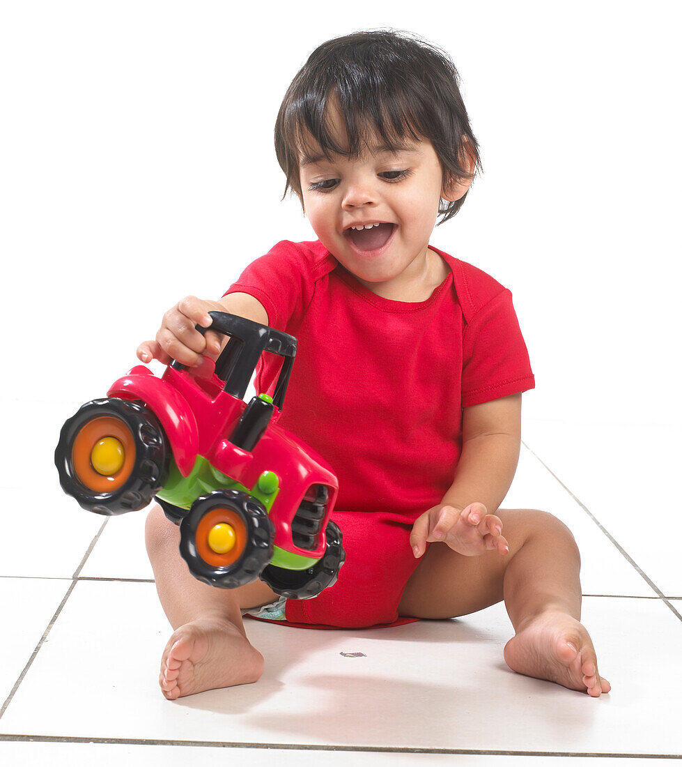 Baby boy sitting with toy tractor