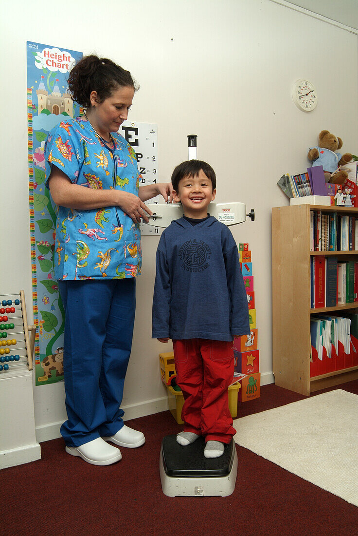 Boy standing on scales next to nurse