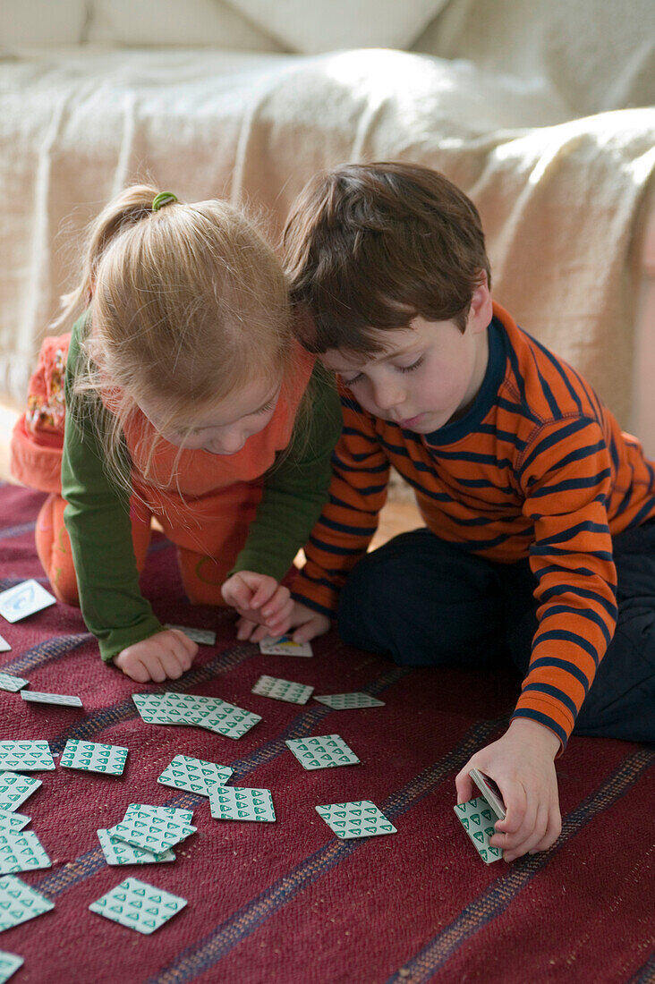 Girl and boy looking at picture cards spread on floor