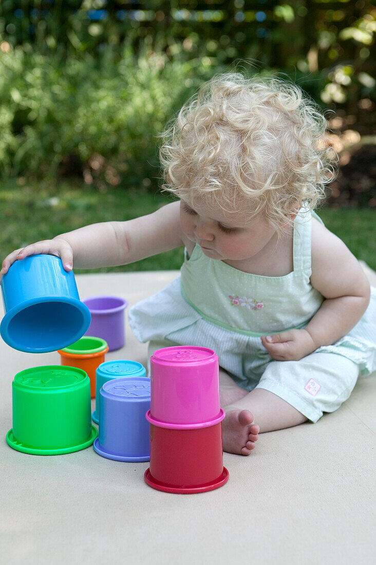 Baby girl playing with plastic cup toys
