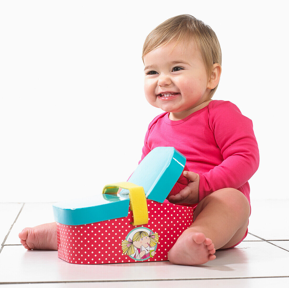 Baby girl sitting playing with toy picnic basket
