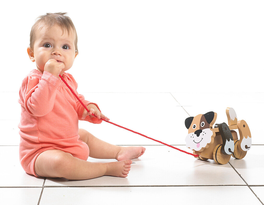Girl sitting playing with pull along dog