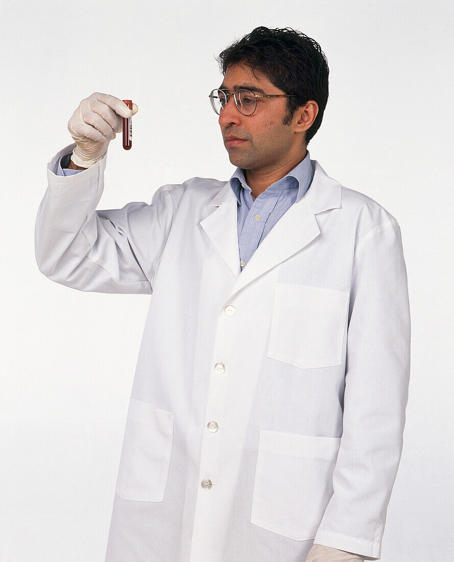 Doctor in laboratory coat holding up a phial of blood