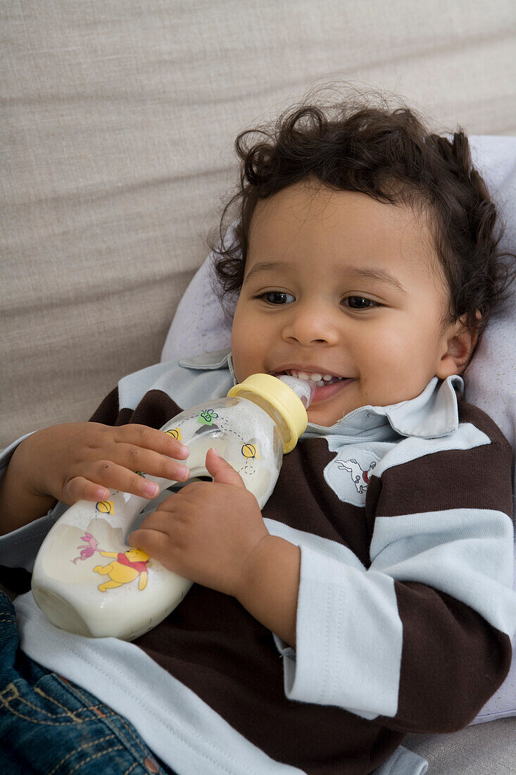 Baby boy with milk bottle in his hands
