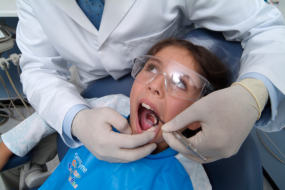 Dentist holding mirror in girl's mouth