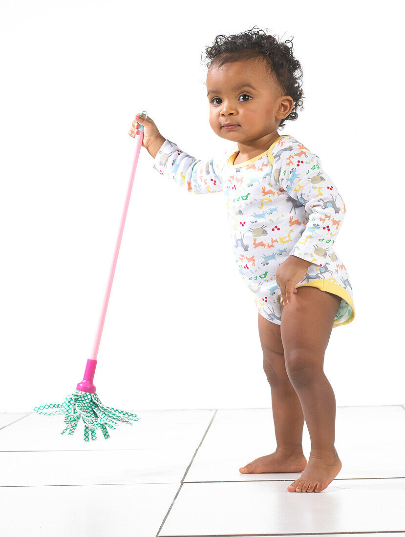 Girl standing holding toy mop