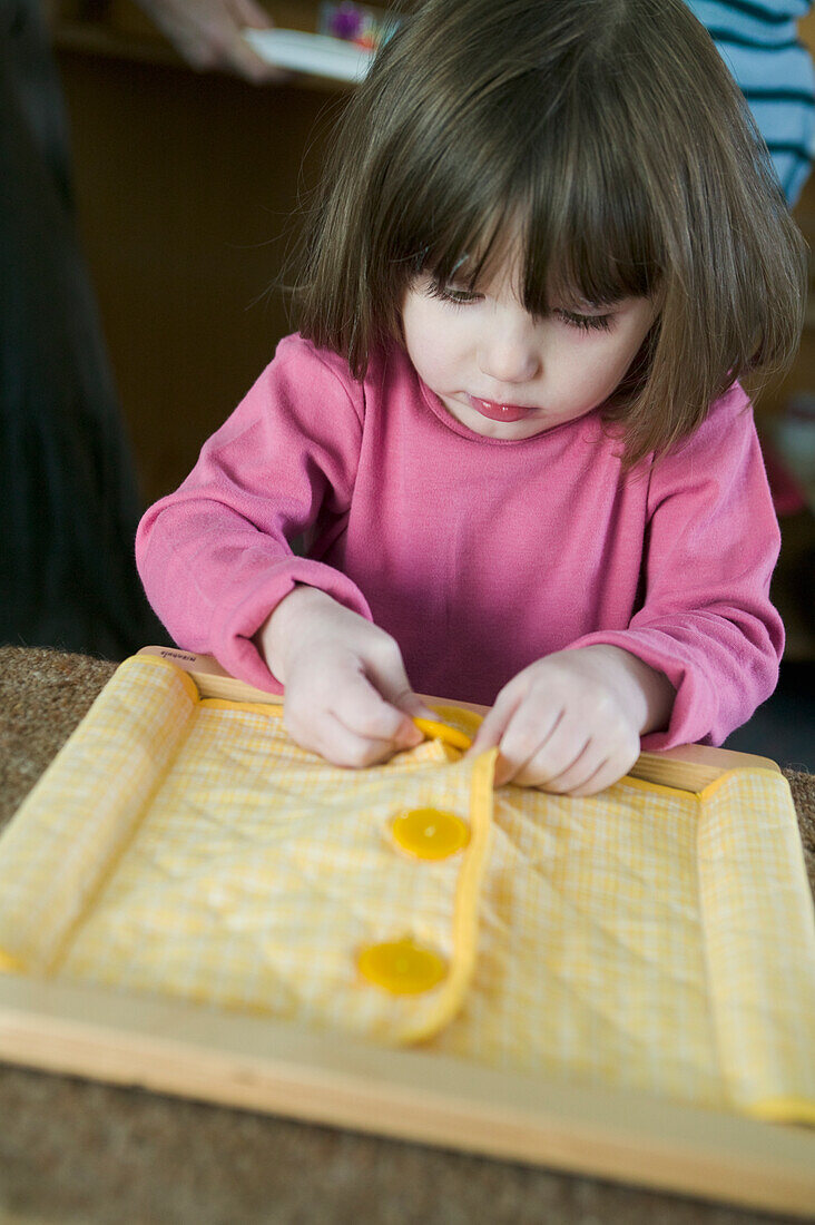 Girl buttoning up fabric in frame