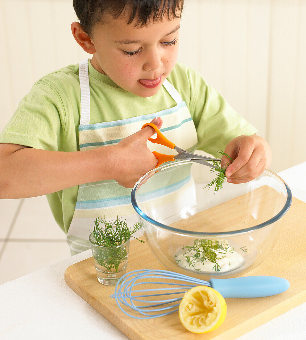 Boy cutting dill into a bowl