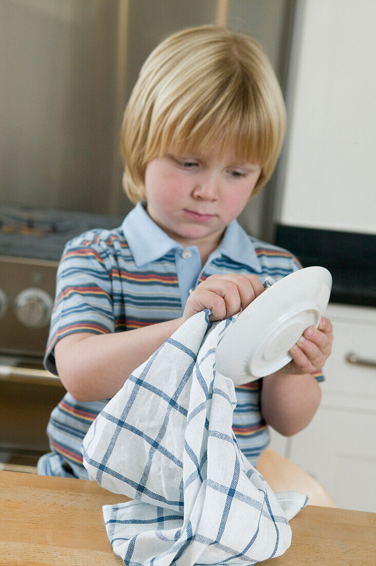 Boy drying plate with tea towel